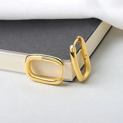 Boucles d'oreilles en forme de O or posées contre un livre